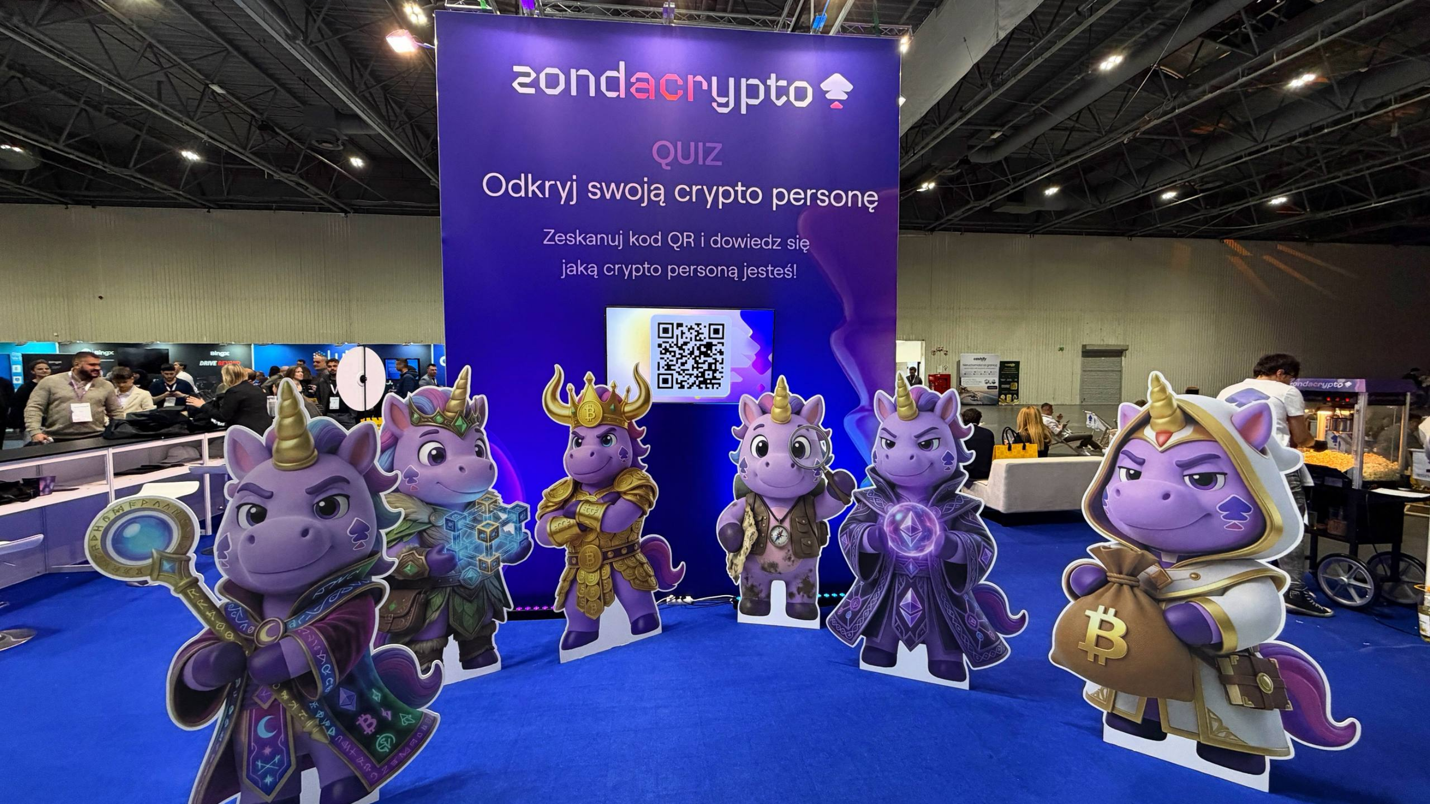A "Discover your crypto persona" quiz booth featuring colorful unicorn cutouts in various costumes.